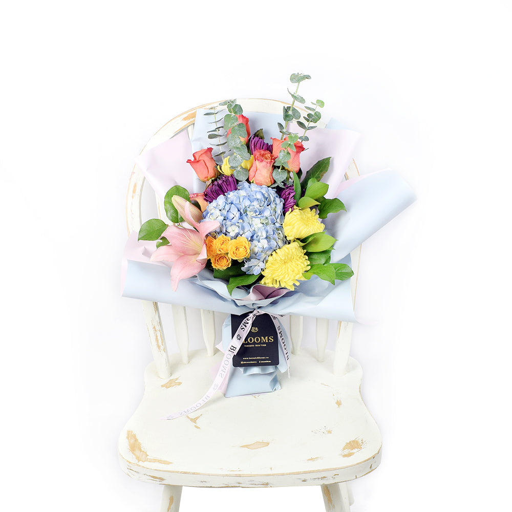 The Festive Purim Bouquet from Vancouver Blooms features a cheerful arrangement of roses, cremons and other flowers tied with a designer ribbon
